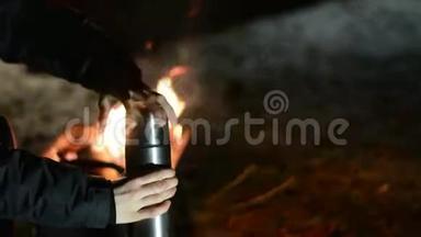 女人把热水瓶里的热茶倒进杯子里。 <strong>寒冷</strong>的<strong>冬夜</strong>。
